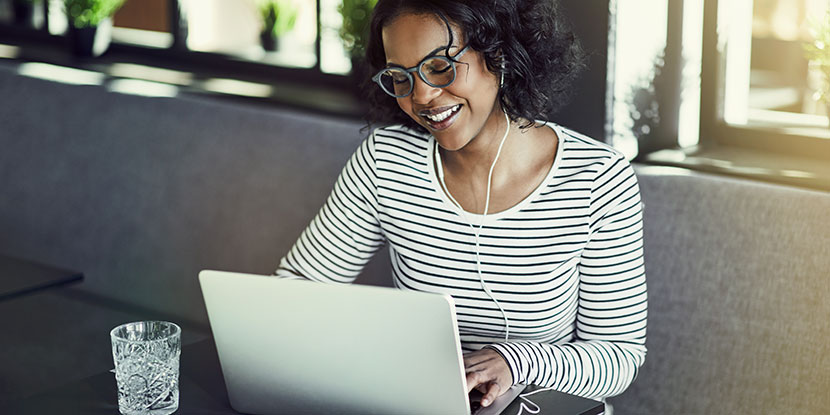 Una mujer usando anteojos mientras trabaja en la computadora.