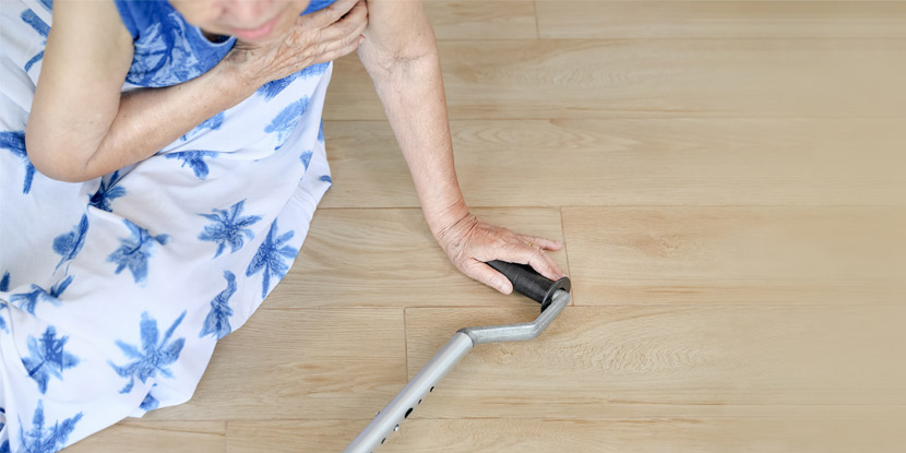 Imagen simulada de una mujer mayor con un bastón que ha caído sobre un piso de madera