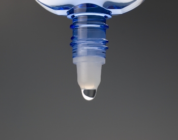 Drop coming out of bottle of eyedrops.
