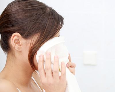 Woman drying her face with a clean white towel.