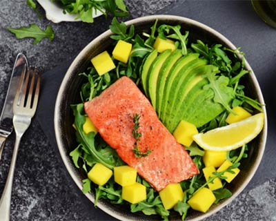 A dinner plate with salmon, salad and avocado