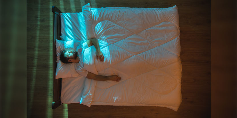 Overhead view of a man sleeping in a bed at night.