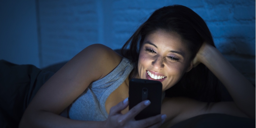 Una mujer usando su teléfono inteligente en la noche