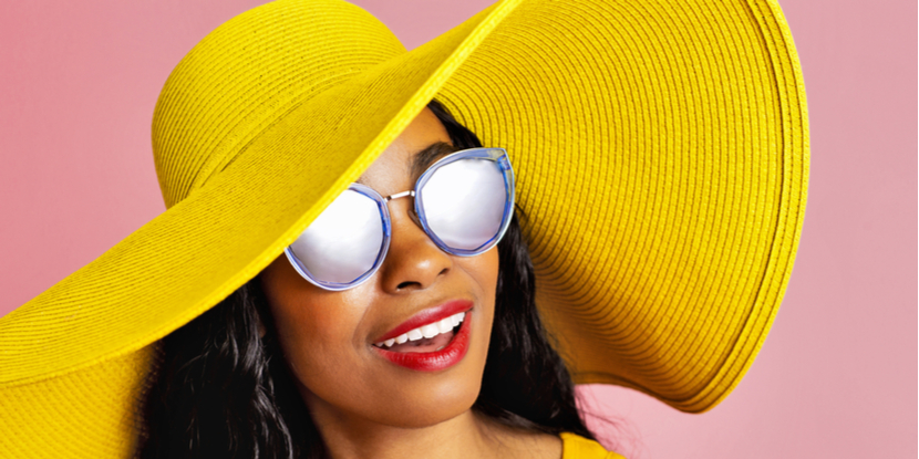 Mujer con sombrero amarillo de ala ancha y gafas de sol oscuras