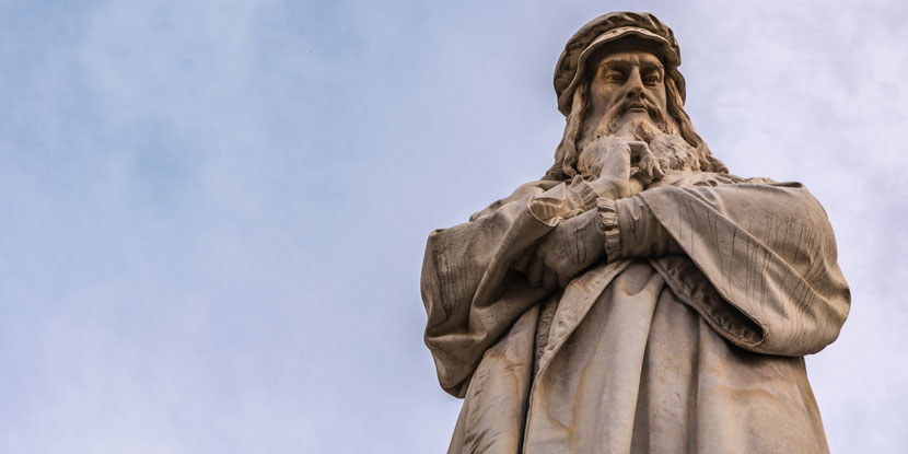 Una estatua de Leonardo da Vinci, quien podría haber tenido estrabismo, vista contra un cielo azul.