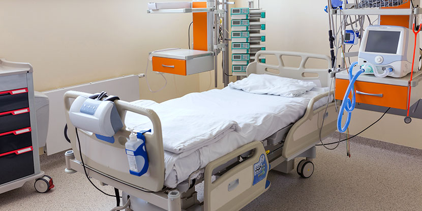 Un ventilador al lado de una cama vacía en la UCI, listo para tratar pacientes con neumonía, influenza o coronavirus (COVID-19).