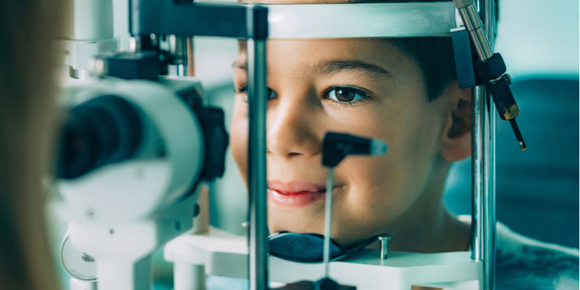 Ophthalmologist uses slit lamp to examine boy and look for signs of inflammation from juvenile idiopathic arthritis uveitis
