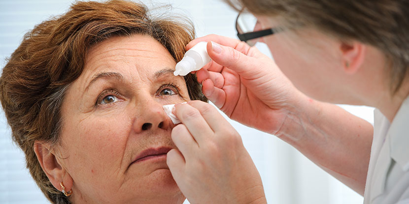 Doctor administering eye drops to older woman