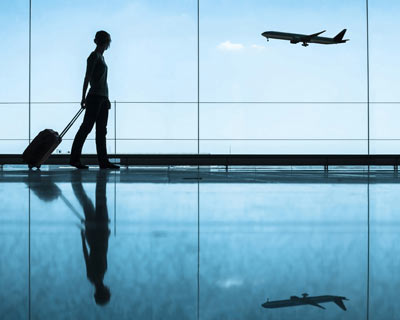 Person in silhouette in airport with airplane taking off in background