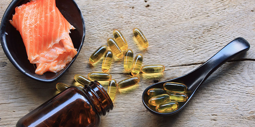 Salmon fillets and fish oil supplements arranged on a kitchen table.