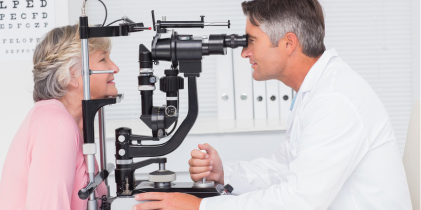 Un doctor y su paciente sentados ante el microscopio de la lámpara de hendidura para un examen