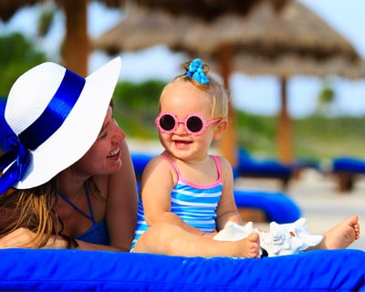 Mother and baby on beach, wearing sunglasses.