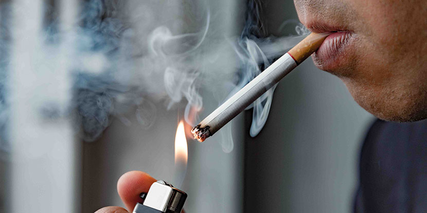 Una fotografía de un joven encendiendo un cigarrillo
