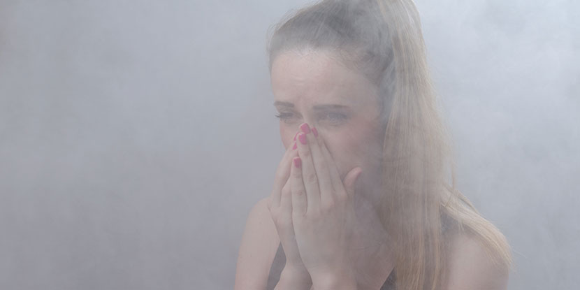 Woman with closed eyes, barely visible in cloud of smoke