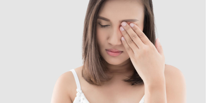 A young woman rubbing her eye, which is irritated from blepharitis