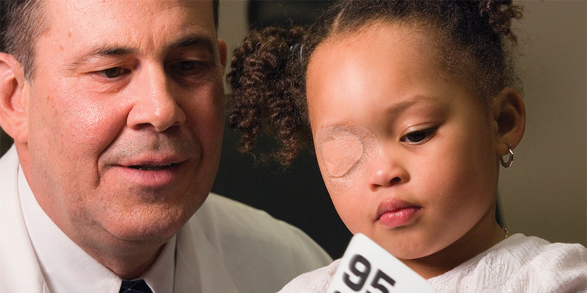 Un oftalmólogo se sienta con un niño cuyo ojo está tapado