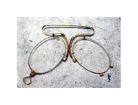 A pair of wire-framed eyeglass lenses joined together by a large spring bridge. There is a small metal loop on one lens.