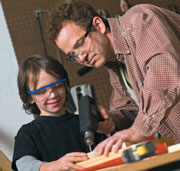 Father and son wearing eye protection while using tools