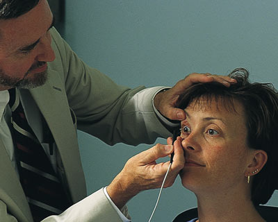 A doctor using pachymetry to measure the thickness of a woman's cornea.