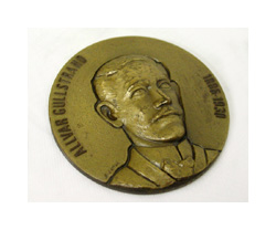 A bronze-colored coin or medal with a man's face on it. He has larger ears and wears a high, stiff collar. The text across the edge of the coin reads: ALLVAR GULLSTRAND.