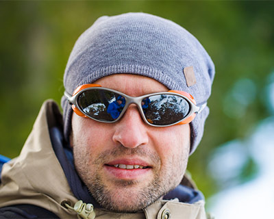 A man is wearing winter clothes and wraparound sunglasses.