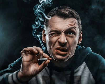 Un hombre está fumando un cigarrillo y molesto por el humo en sus ojos.