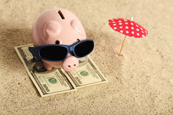 Piggy bank on the beach with sunglasses