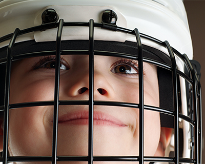 A smiling boy wears a hockey helmet