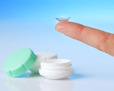 Contact lens case and hand with contact lens on fingertip.