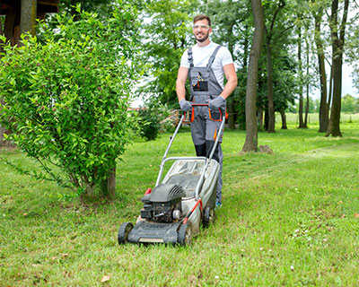 A man is mowing his lawn while wearing safety glasses or protective eyewear