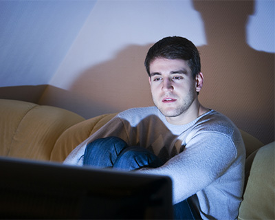 A man is watching TV in a dark room