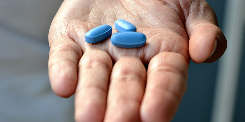 Tres píldoras azules en la palma de la mano de un hombre