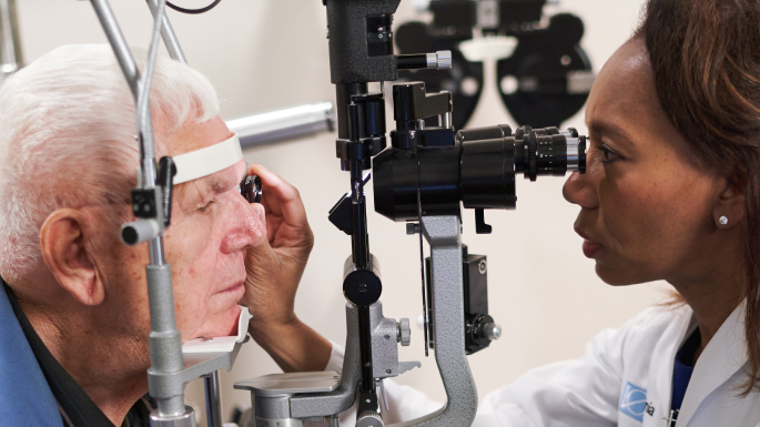 Ophthalmologist using slit lamp to examine man's eyes.