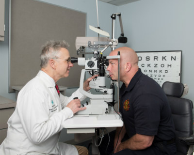 Thomas Steinemann, MD, examines firefighter Jay Northup's eyes to monitor his vision and his recovery as he continues to heal from the fireworks explosion that almost blinded him.
