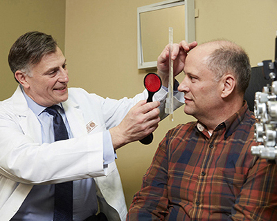 Stephen Lipsky, MD, performs an eye exam on a patient in his office