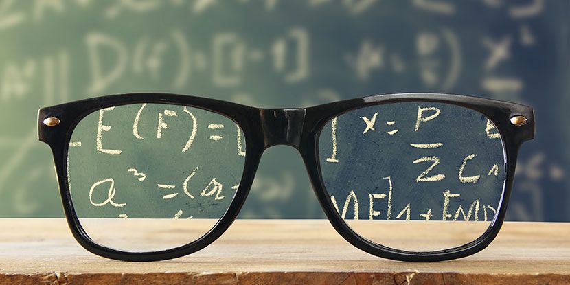 Glasses on a stack of books with classroom chalkboard in background